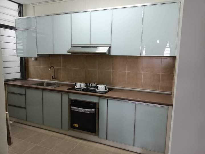 A grey-green kitchen with a brown tiled backsplash, a built-in oven, a sink and a hob.